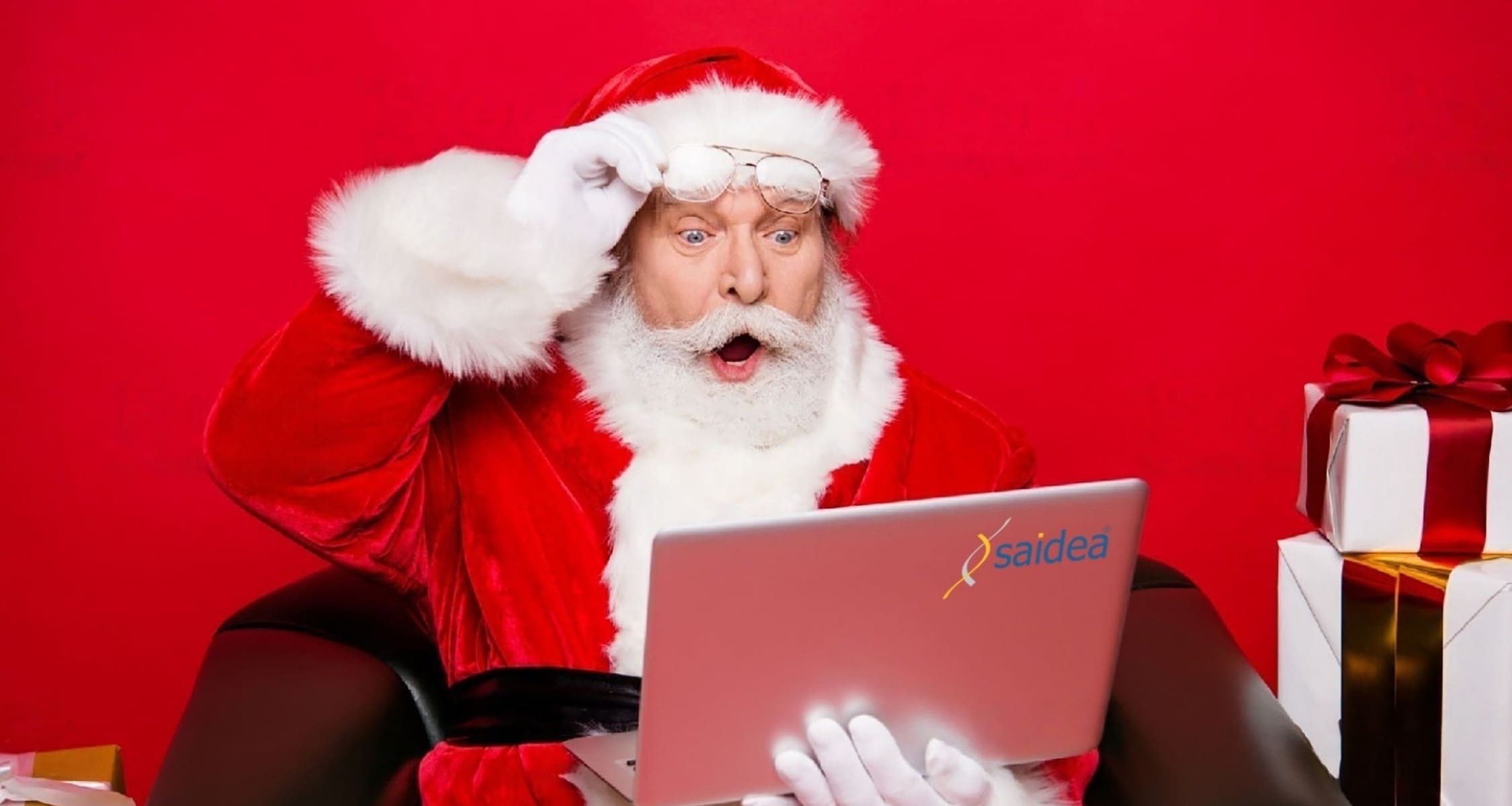 Babbo Natale con la faccia stupita che tiene in mano un computer marchiato Saidea
